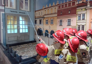 dzieci w zawodzie strażaka gaszą pożar w kawiarni Płomyczek.