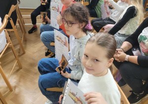 Uczniowie siedzą i chwalą się zdobytymi nagrodami.