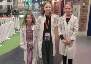 Zosia, Hania i Kaja stoją w miasteczku Miniciti w strojach lekarskich.