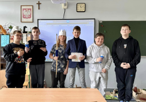 Po zakończonym pokazie uczniowie stoją pod tablicą i pozują do wspólnego zdjęcia.