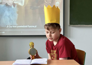 Dominik siedzi przy ławce i odpowiada na kolejne pytanie dziennikarki.