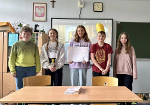 Po zakończonym pokazie uczniowie stoją pod tablicą i pozują do wspólnego zdjęcia.