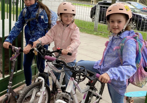 Uczennice przyjeżdżając na rowerach i hulajnodze nie zapomnialy o bezpieczeństwie - na głowach mają kaski.