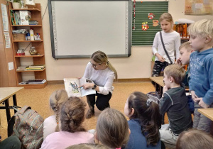 Pani Marlena pokazuje dzieciom album o rycerstwie polskim.