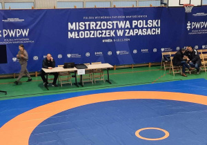 Hala gimnastyczna, w której odbywały się mistrzostwa. Na drabinkach wisi duzy baner w kolorze granatowym z napisem "Mistrzostwa Polski Młodziczek w zapach".