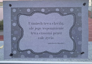 Na szkolnym korytarzu, w oknie wisi przysłowie "Uśmiech trwa chwilę, ale jego wspomnienie trwa czasami przez całe życie".