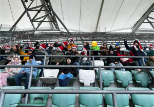 Uczniowie siedzą na trybunie stadionu i słuchają historii klubu.