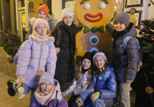 Uczniowie znajdują się na rynku miasta i pozują do grupowego zdjęcia.