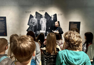 Uczniowie stoją i słuchają o historii fanryki i jej założycielach.