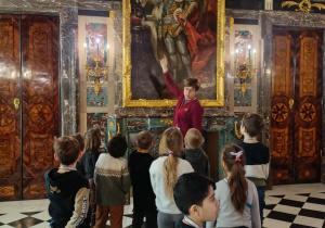 Dzieci podziwiają portret króla i portrety jego poprzedników.