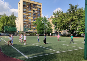 Uczniowie rozgrywają mecz na boisku.