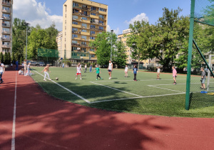 Uczniowie rozgrywają mecz na boisku.
