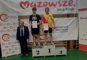 Adam stoi na podium podczas dekoracji medalami i dyplomami.