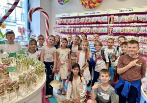 Uczniowie, stoją w sklepie i pozują do grupowego zdjęcia.