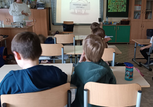 Uczniowie siedzą w ławkach i oglądają prezentację "Higiena jamy ustnej".