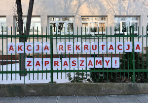 Akcja Rekrutacja. Zapraszamy! - napis ułożony z czerwonych liter wisi na parkanie szkoły.