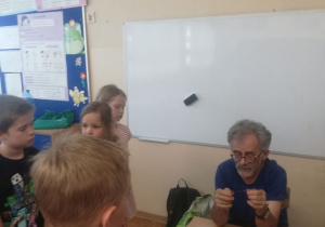 Prowadzący zajęcia objaśnia dzieciom kolejne etapy wykonania ozdób z drutu miedzianego.