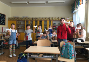 Uczniwie, trzymając w rękach, chwalą się wykonanym origami.
