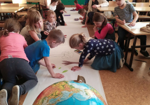 Uczniowie, po wysłuchaniu wstępu do zajęć, na długim rulonie z papieru rysują Ziemię.