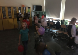 Dzieci tańczą i bawią się z balonami.