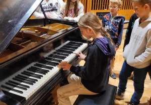 Studio nagrań dźwiękowych - dzieci stoją cierpliwie w kolejce do zagrania na studyjnym fortepianie. Przy klawiaturze Kaja Mudel..