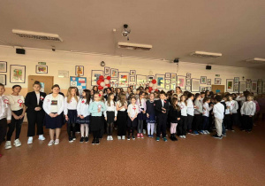 Uczniowie z kals 4-8 stoją na korytarzu i śpiewają hymn Polski.