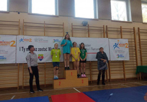 Katarzyna z klasy 6a stoi na podium, na pierwszym miejscu, podczas dekoracji medalami.