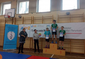 Adam z klasy 6a stoi na podium, na drugim miejscu, podczas dekoracji medalami.