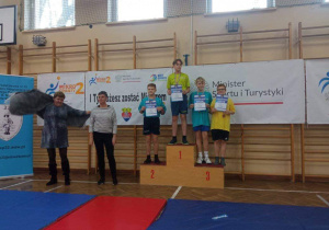Chłopcy stoją stoi na podium, na drugim i trzecim miejscu, podczas dekoracji medalami.