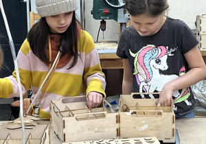 Dziewczynki dobierają odpowiednie elementy do swoich konstrukcji.