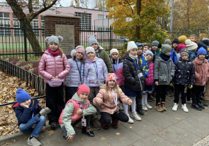 Uczniwie z klas pierwszych stoją pod szkołą.