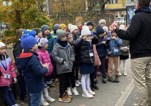 Uczniwie z klas pierwszych stoją pod szkołą.