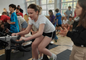 Uczennica naszej szkoły wykonuje zadanie na rowerku stacjonarnym.