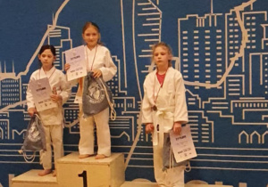 Hanna stoi na podium na pierwszym miejscu podczas dekoracji medalami. W ręku trzyma dyplom i nagrodę.