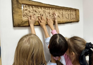 Trzy dziewczynki dotykają obrazek wykonany ploterem frezującym i podziwiają precyzję z jaką został wykonany.