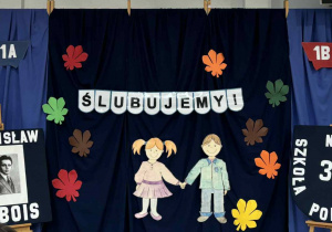 Dekoracja szkolna: napis :Ślubujemy!", zdjęcie patrona szkoły - Stanisława Dubois oraz tarcza szkoły.