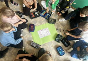 Uczniowie tworzą plakat z okazji "Światowy Dzień Zwierząt" na kartonie w kolorze zielonym.