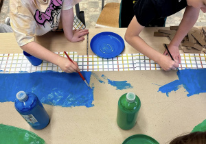 Uczniowie malują tło - niebo w kolorze niebieskim.