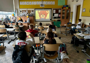 Pierwszoklasiści oglądają filmik edukacyjny "Jak narysować Misia?".
