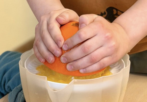 Chłopiec wyciska sok z pomarańczy.