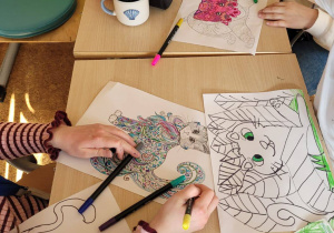 Uczennice kolorują kolorowanki z wizerunkiem kota.