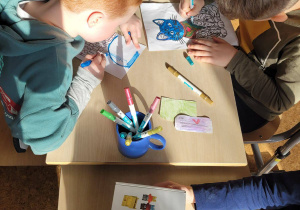 Chłopcy kolorują kolorowanki z wizerunkiem kota.