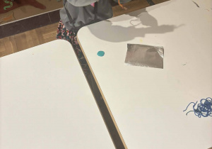 Dziewczynka, stojąc przy stoliku, wykonuje "Zośkę".