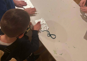 Chłopcy, stojąc przy stole, wykonują swoje zabawki.