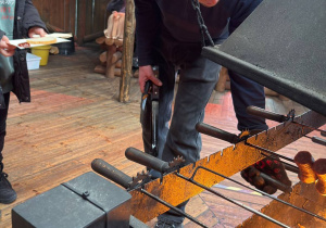 Kiełbaski pieką się nad ogniskiem.