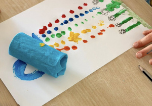 Uczeń maluje farbami.