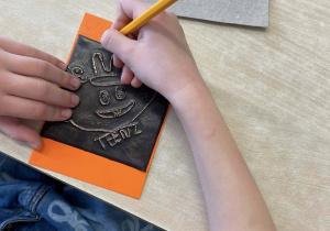 Uczennica prezentuje gotową pracę plastyczną.