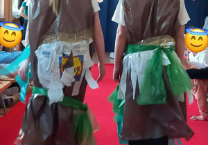 Duet dziewczynek prezentuje stroje z materiałów recyklingowych na wybiegu.