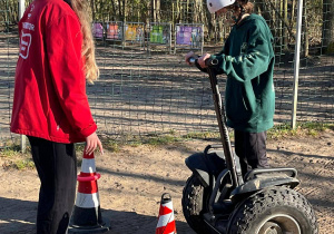 Chłopiec, pod okiem Pani instruktor, jeździ na segwayu.