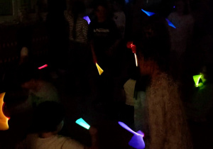 Uczniowie trzymają w rękach światła odblaskowe podczas nocnej wyprawy świetlików.